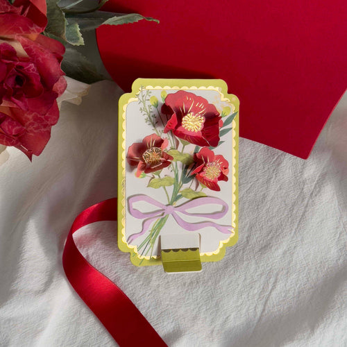 Decorative card with floral design and red ribbon on a white fabric background