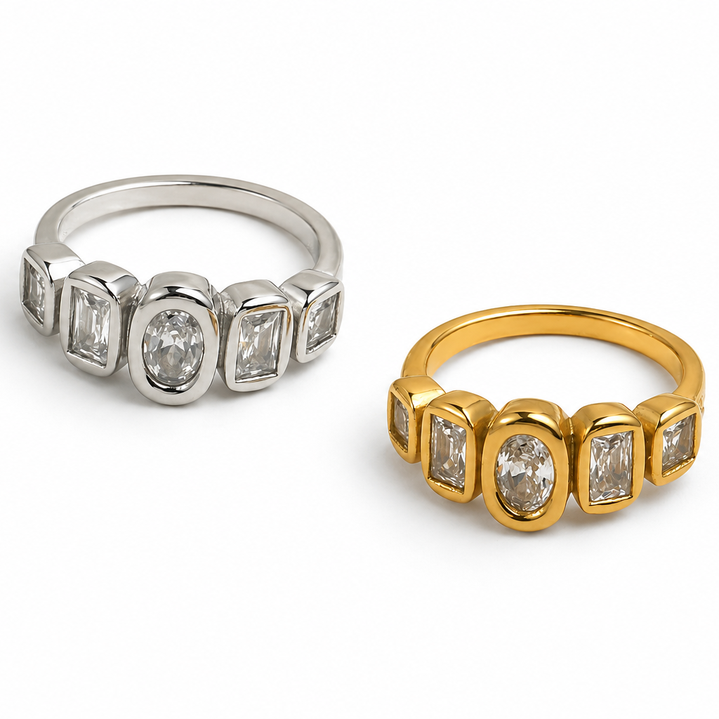 Two rings shown on a white background: one in silver-toned metal and one in yellow gold-toned metal, both featuring a row of baguette and oval-cut stones.