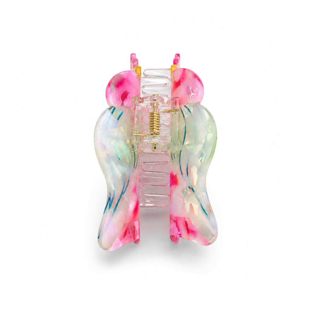 A translucent seashell-shaped hair claw clip in a vibrant multicolor design, featuring pink, yellow, blue, and green swirls with rhinestone accents, set against a plain white background.