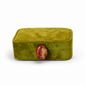 An olive green velvet ring box shown in two views: closed with a red oval clasp on the left, and open with white interior compartments, a mirror on the lid, and a small ring inside on the right, set against a plain white background.
