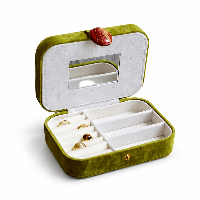 An olive green velvet ring box shown in two views: closed with a red oval clasp on the left, and open with white interior compartments, a mirror on the lid, and a small ring inside on the right, set against a plain white background.